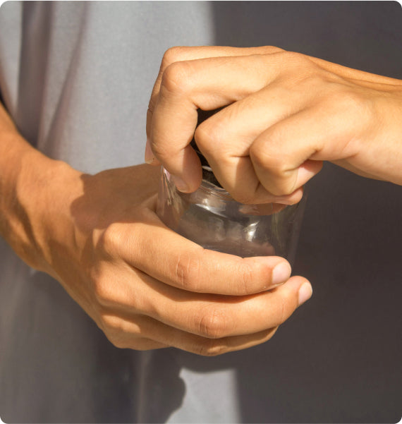 Close-up of hands using a pepper grinder against a neutral background